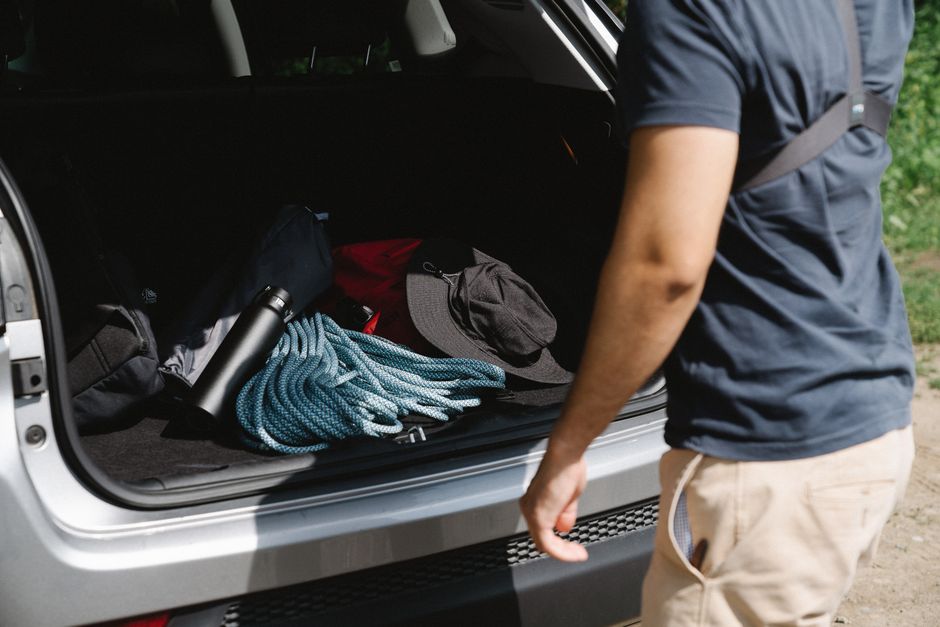 Man organizing camping gear in car trunk, ready for adventure.